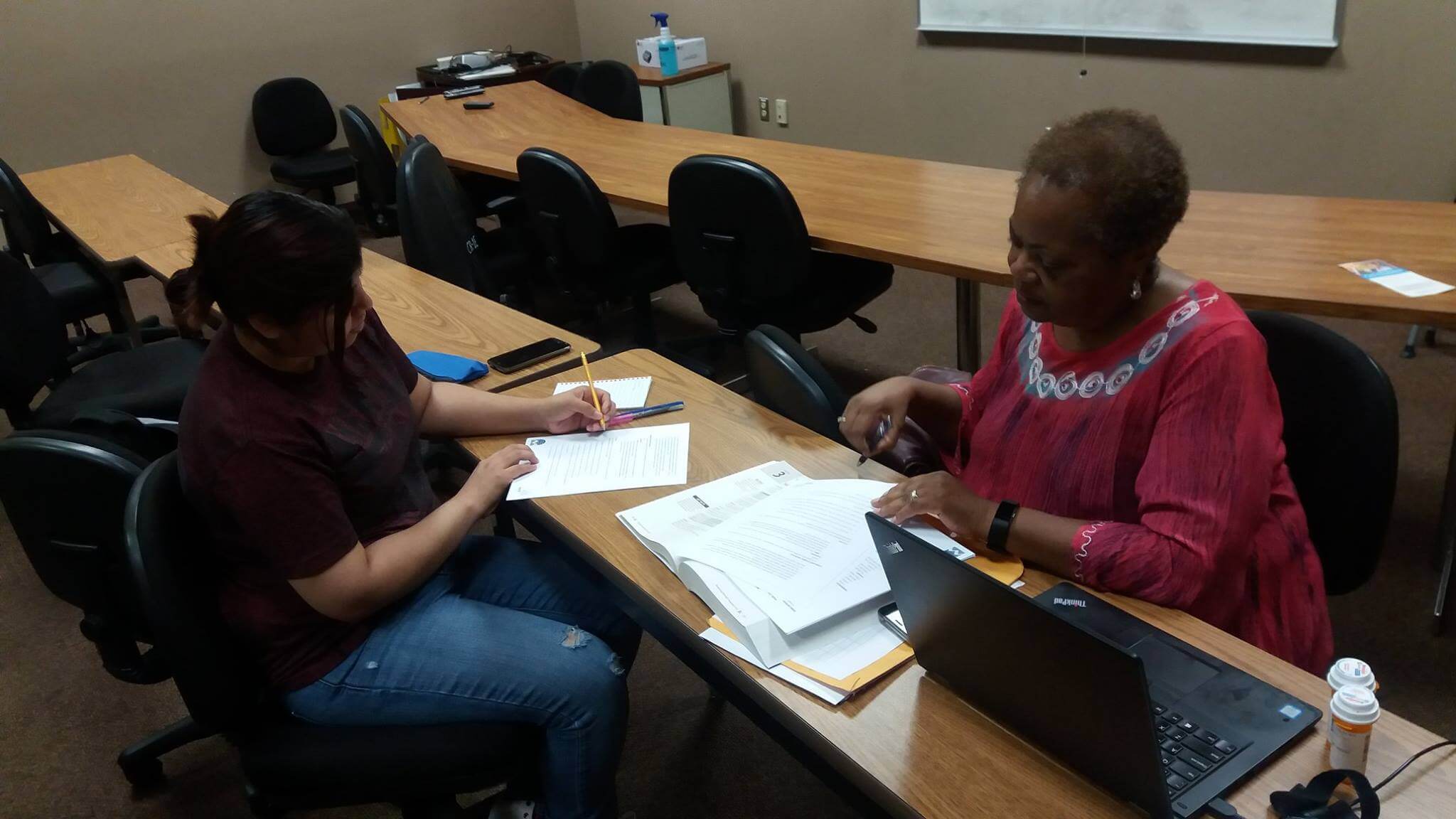 Dos adultos conversan y trabajan juntos en la clase de Servicios para Adultos del DHDC